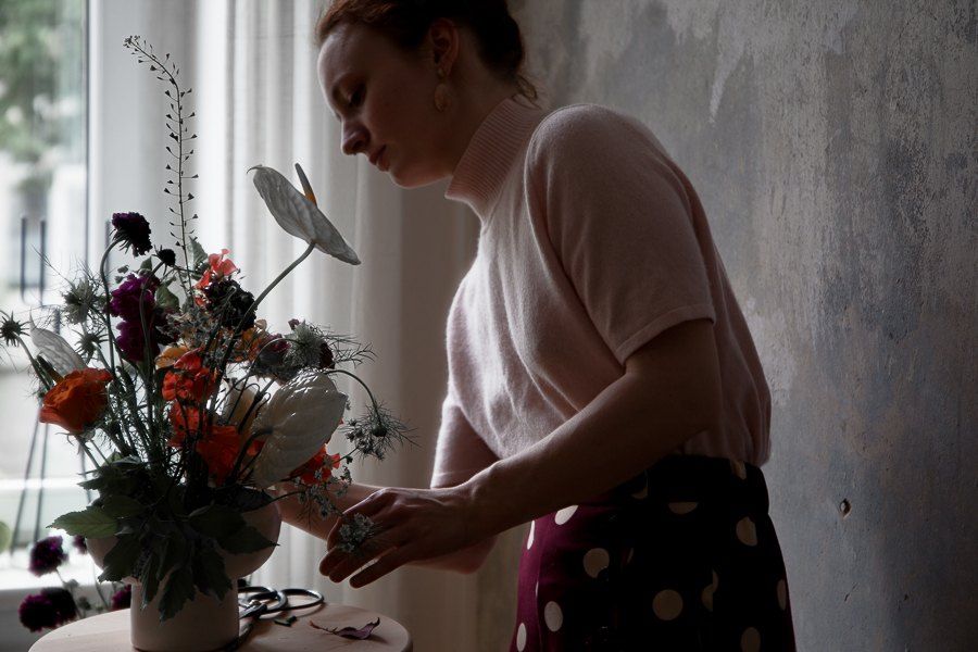 Daniela arrangiert einen Strauß mit Mohn, Anthurie und Skabiosen am Fenster